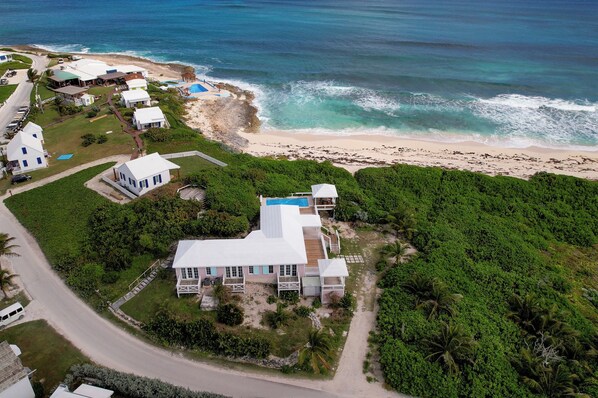 Vista aérea de una propiedad costera con una casa grande, una piscina y una playa.