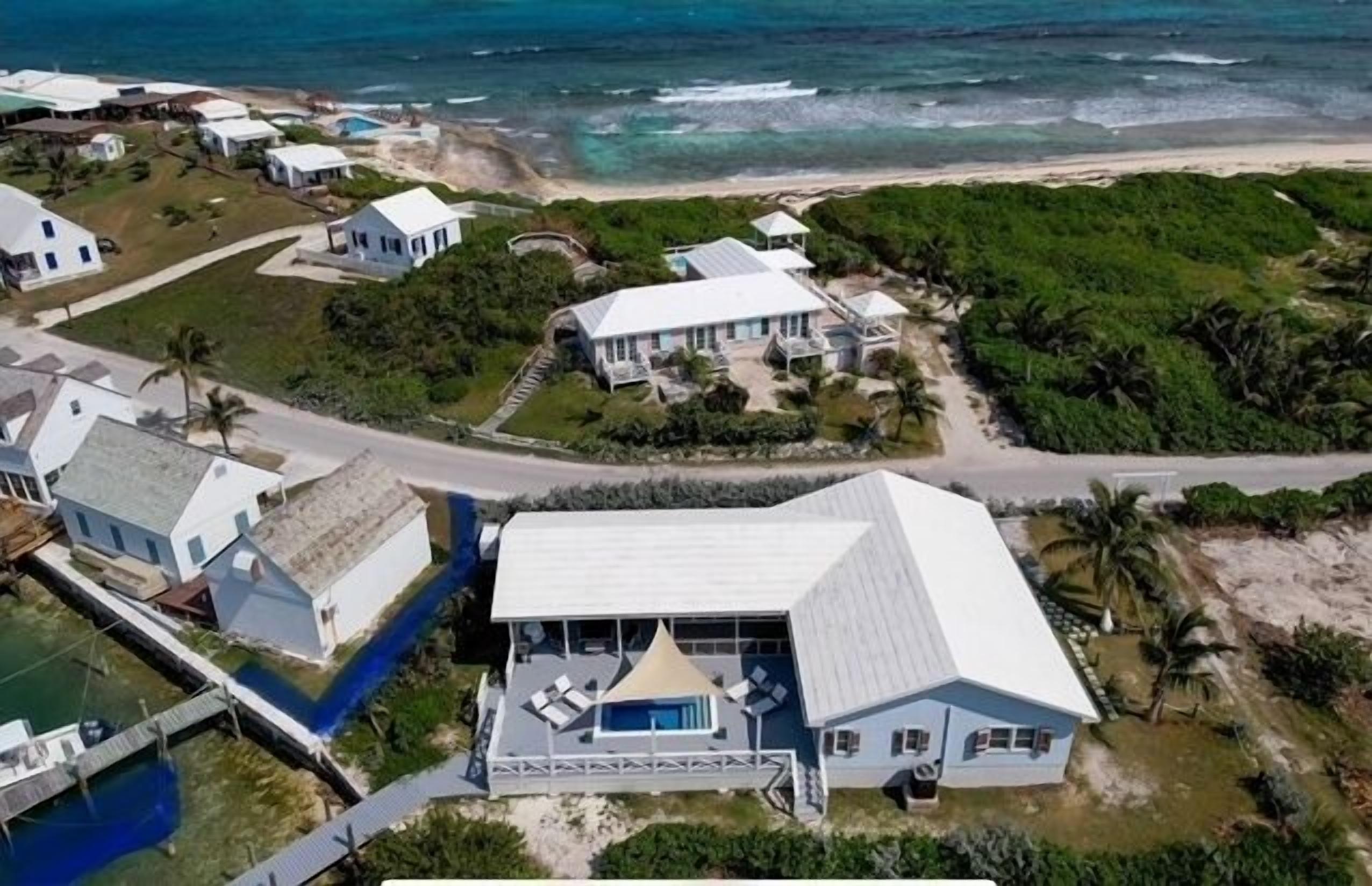 An aerial view of a coastal property with multiple buildings, a swimming pool, and a beach.