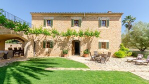 Un edificio in pietra con un cortile, posti a sedere all'aperto e una veranda coperta.