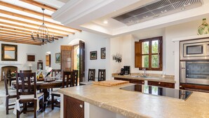 Un'ampia cucina con una grande isola, travi in legno a soffitto ed elettrodomestici moderni.