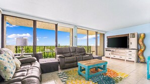 A spacious balcony with a sofa, a coffee table, and a TV. - Lovely 2 Bedroom/ 2 Bath Across Siesta Key Beach! (Siesta Key)