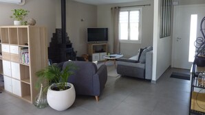 Una sala de estar moderna con chimenea, televisor, sofá y estantería.