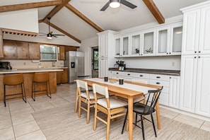 Enjoy meals at the central island with bar stools, surrounded by white cabinetry and a stainless steel refrigerator.