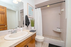 Bathroom features a double sink, shower area, and a wooden vanity with a countertop.