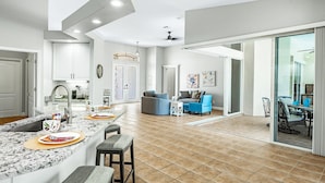 A spacious kitchen with a large island, a dining area with a table and chairs, and a living room with a sofa and a coffee table. - Pet friendly villa; gulf access canal w/elec heated pool & pretty views! Villa Sienna - SWFL Rentals (Cape Coral)