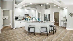 A spacious kitchen with a large island, white cabinetry, and a tiled floor. - Pet friendly villa; gulf access canal w/elec heated pool & pretty views! Villa Sienna - SWFL Rentals (Cape Coral)