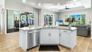 A modern kitchen with white cabinets, a granite countertop, and a built-in dishwasher. - Pet friendly villa; gulf access canal w/elec heated pool & pretty views! Villa Sienna - SWFL Rentals (Cape Coral)