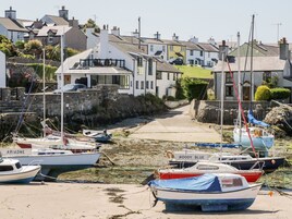 Un puerto con barcos amarrados, un estrecho camino entre edificios y un muro de piedra en un lado.