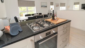 A modern kitchen with a central island, built-in oven, and a dining area with a view of the outdoors.