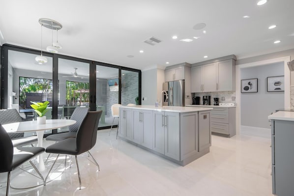 Enjoy casual dining in this kitchen with a central island and ample counter space, adjacent to a dining area with a table and chairs.