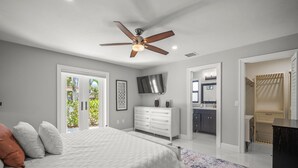 A bedroom with a bed, a ceiling fan, a dresser, and a TV. - Stylish & Bright 3-Bedroom Home with Backyard, Bikes & Pool by Esthetic Stays (Naples)
