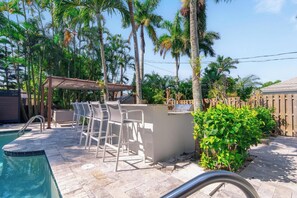 Relax by the serene pool surrounded by lush greenery and a shaded seating area.