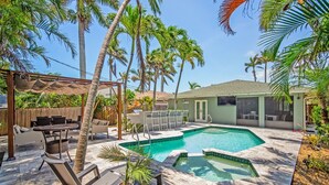 A backyard with a swimming pool, outdoor furniture, and palm trees. - Stylish & Bright 3-Bedroom Home with Backyard, Bikes & Pool by Esthetic Stays (Naples)