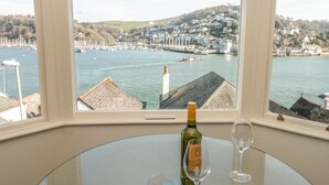 Una mesa con una botella de vino y una copa, con vista a un puerto con barcos y edificios.