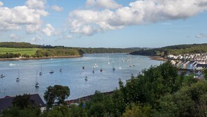 A coastal town with a marina filled with sailboats, surrounded by lush greenery and residential buildings. - Anchors Rest (Y Felinheli)