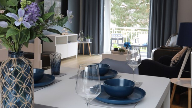 A dining area with a white table set for two, blue bowls, and wine glasses. - Anchors Rest (Y Felinheli)