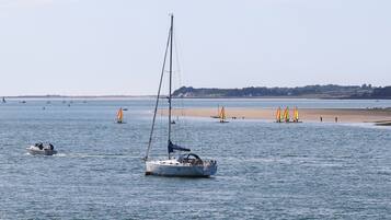 A calm bay with sailboats and a sandy beach.