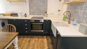A modern kitchen with dark cabinets, a built-in oven, a white countertop, and a patterned backsplash.