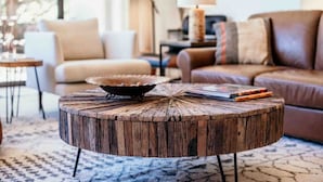 A round wooden coffee table with a decorative bowl on top, placed in a living room with a sofa and a lamp in the background. - Luxury West Sedona home close to everything (Sedona)