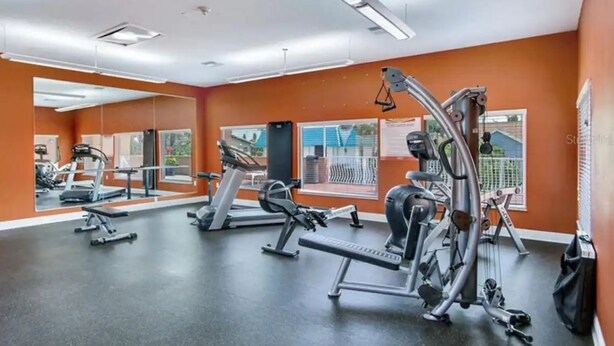 A gym with various exercise machines, large mirrors, and orange walls. - Beautiful 2 bedroom 2 Bath directly across from Gulf (North Redington Beach)