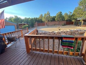 Enjoy the serene view from the deck, surrounded by a fenced backyard with a covered area and stone wall.
