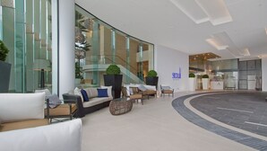 Een moderne lobby met zithoeken, een trap en een receptiebalie.