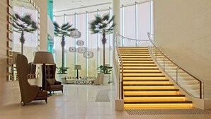 Een ruime lobby met een moderne trap, comfortabele zitplaatsen en decoratieve details.