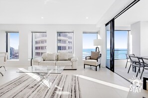 Relax in a spacious living room with expansive city and sea views, a large sofa, and a separate dining area.