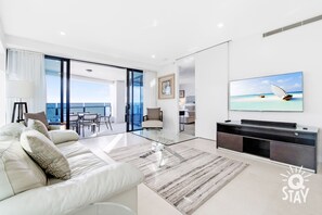 Relax in this stylish living area with a large flat-screen TV, comfortable sofa, and ocean views through the sliding glass door.
