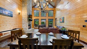 Un interior de madera con una mesa de comedor preparada para cuatro personas, una chimenea y una pared de piedra.
