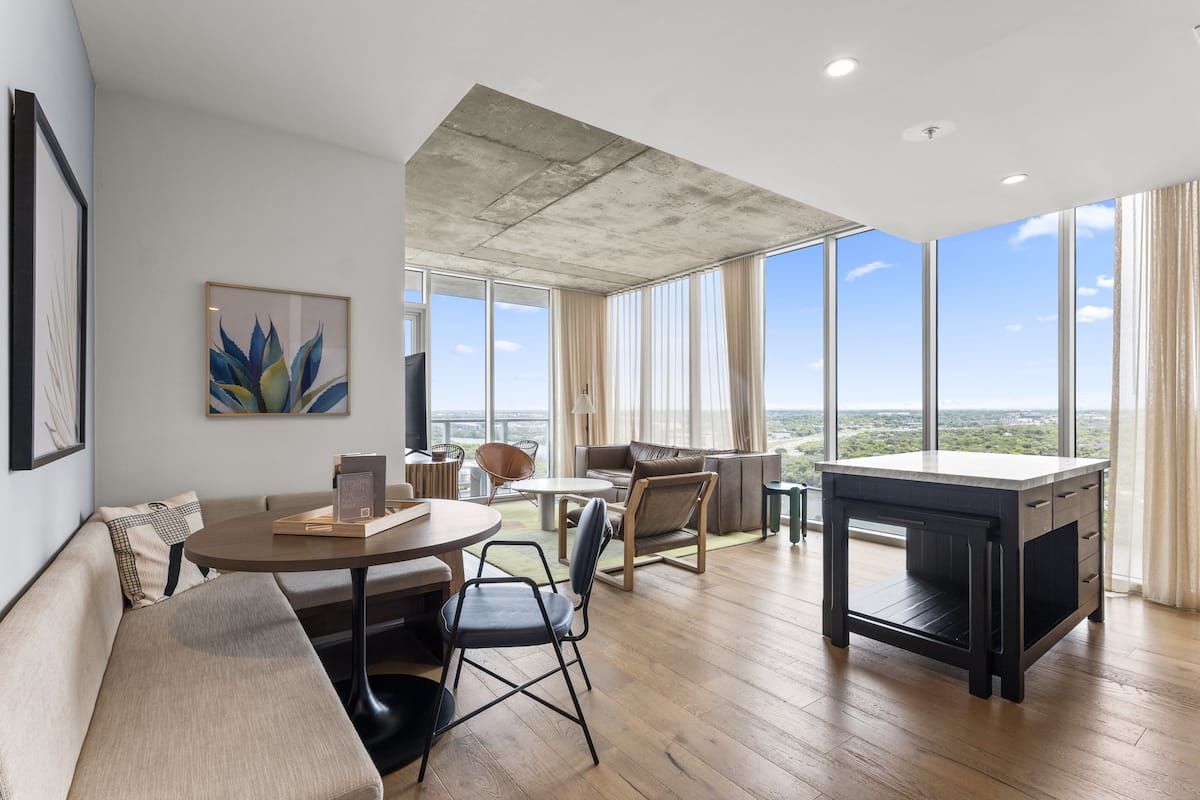 A spacious living area with a large window, a sofa, a dining table, and a coffee table.