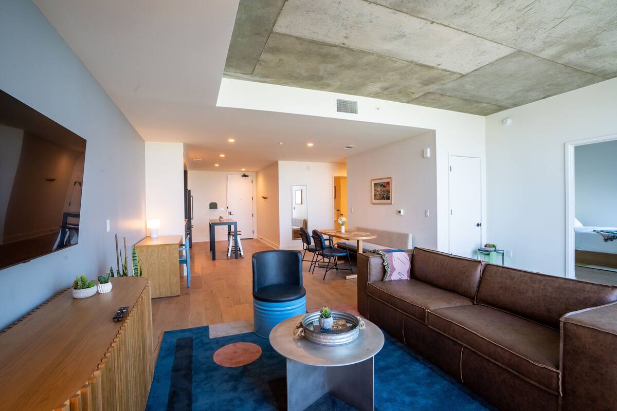 A modern living room with a wooden coffee table, a brown leather sofa, and a blue armchair.