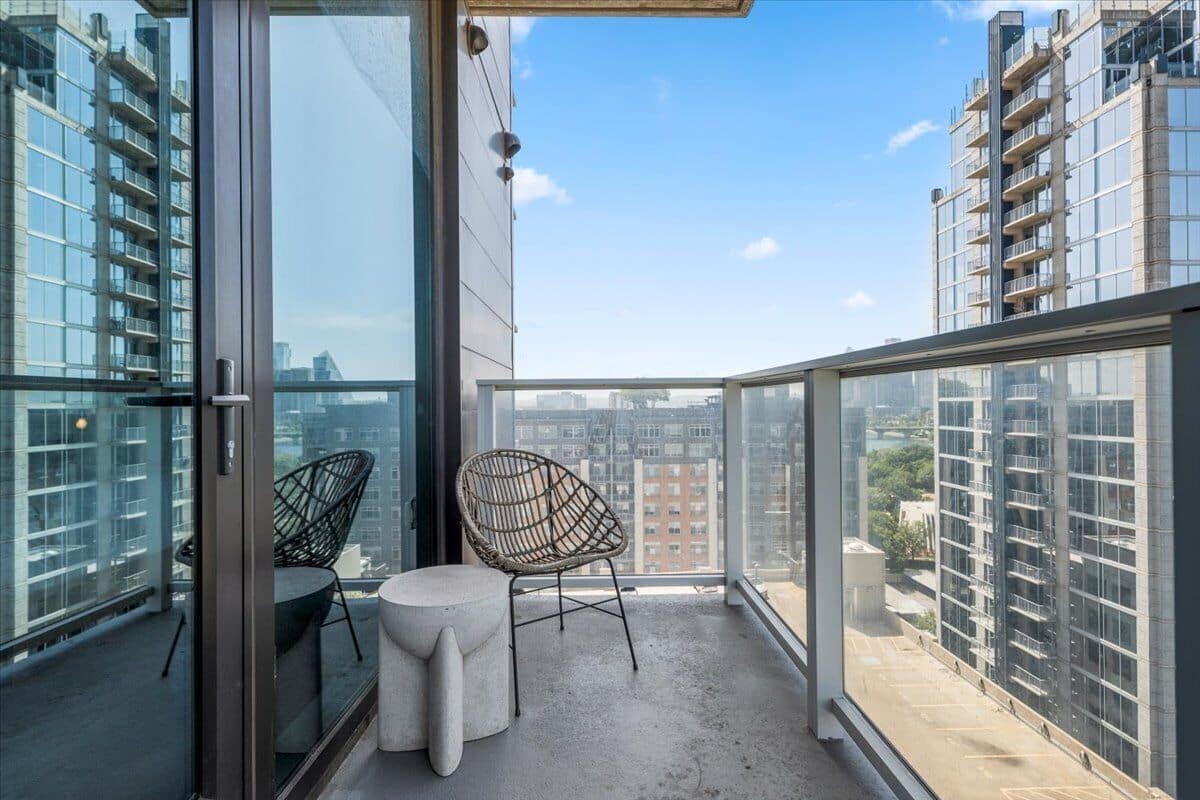 A balcony with a glass door, two wicker chairs, and a small round table.