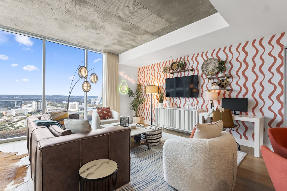 A modern living room with a city view, a large window, and a wavy patterned wall.
