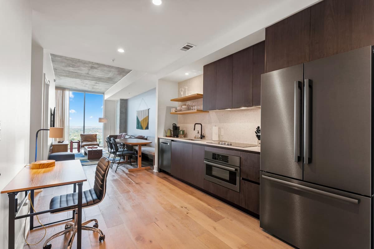 A modern kitchen with dark wood cabinets, stainless steel appliances, and a wooden dining table with chairs.