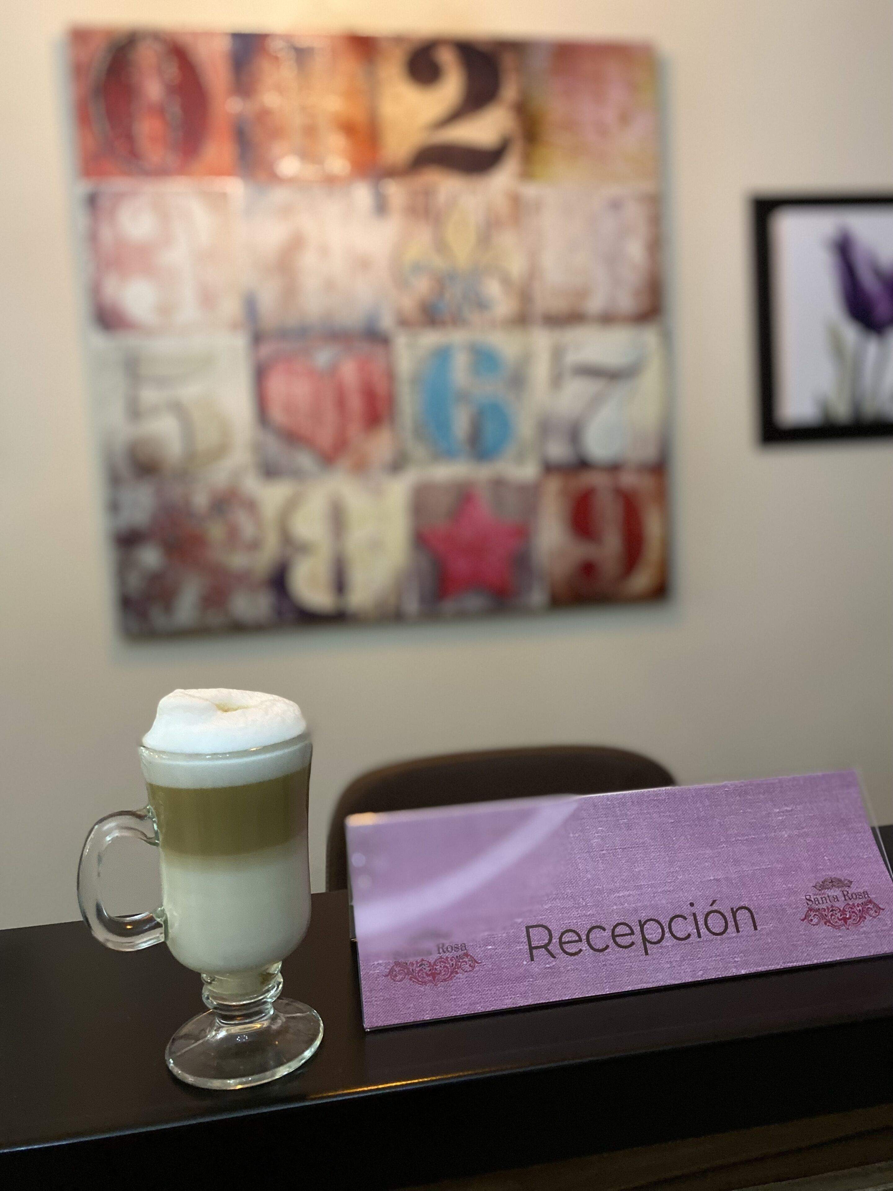 Zona de recepción con una taza de café sobre una mesa y un cartel que dice 