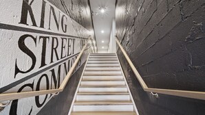 A staircase with a wooden handrail and white steps leading up to a lighted area at the top. - ★1/2 Block to King Street, King Bed ~ Free Parking★ (Alexandria)