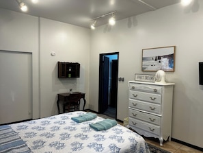 A bedroom with a bed, dresser, desk, and a door leading to another room. - Private, beautiful apartment in historic district (Ocala)
