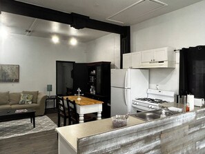 Une cuisine compacte équipée d’un réfrigérateur, d ’une cuisinière et d’un évier. Un coin repas avec une table et des chaises est également disponible.