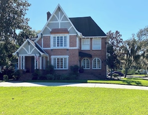 A two-story house with a prominent front porch, a brick facade, and a well-maintained lawn. - Private, beautiful apartment in historic district (Ocala)
