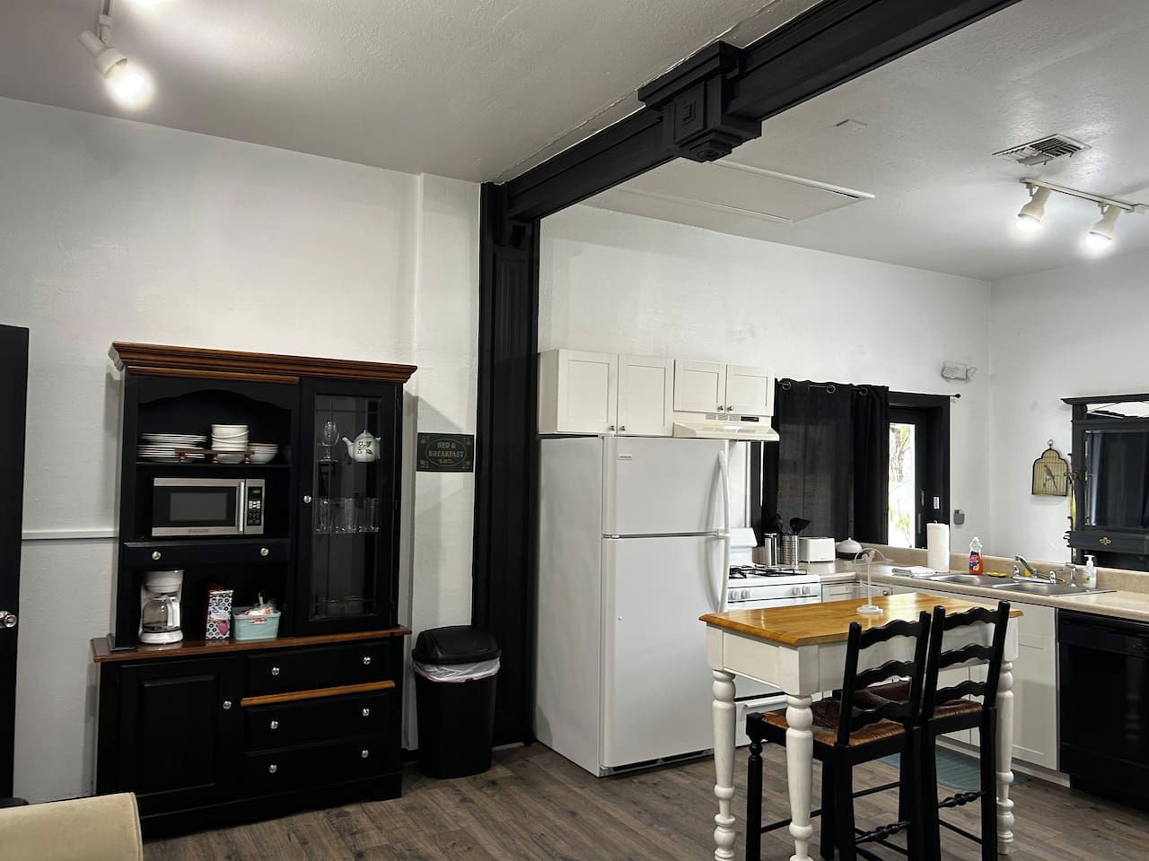 Een moderne keuken met een eethoek, witte kastjes, een magnetron en een koelkast.