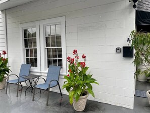 Une véranda avec deux chaises et une plante en pot.