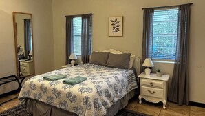 Een slaapkamer met een bed, twee nachtkastjes, een spiegel en een raam met gordijnen.