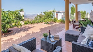 An outdoor patio with wicker furniture, a wine bottle, and a book.