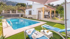 Une piscine avec des chaises longues et un patio couvert.