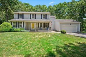 A two-story house with a front porch, a garage, and a well-maintained lawn.