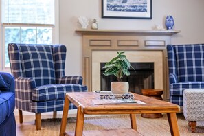 A living room with plaid sofas, a wooden coffee table, and a fireplace.