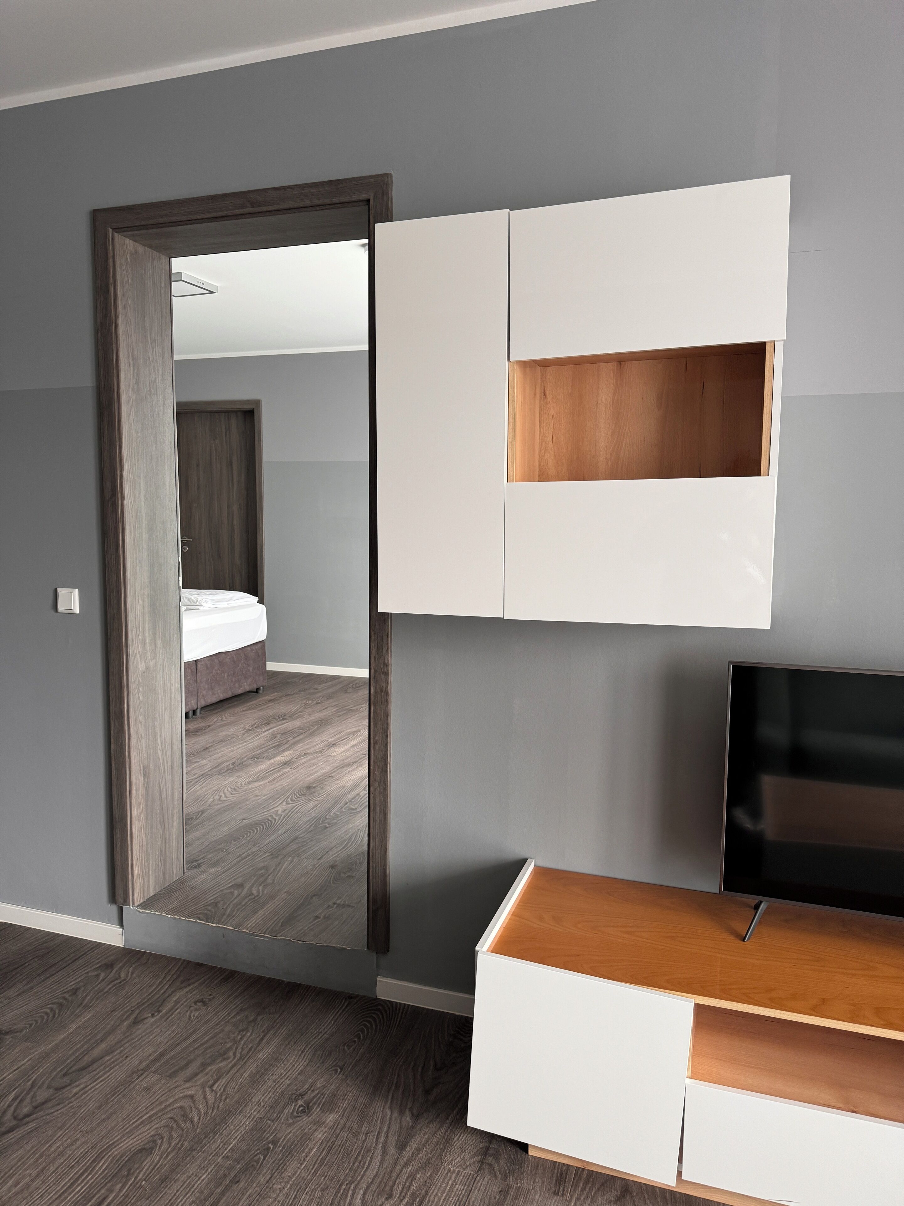 A modern bedroom with a bed, a TV, and a wardrobe.
