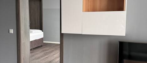 A modern bedroom with a bed, a TV, and a wardrobe.