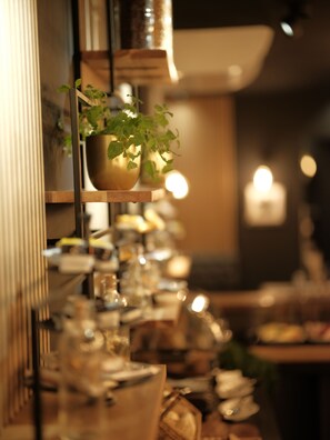 L’intérieur d’un restaurant avec un long comptoir, des plantes suspendues et un éclairage chaleureux.